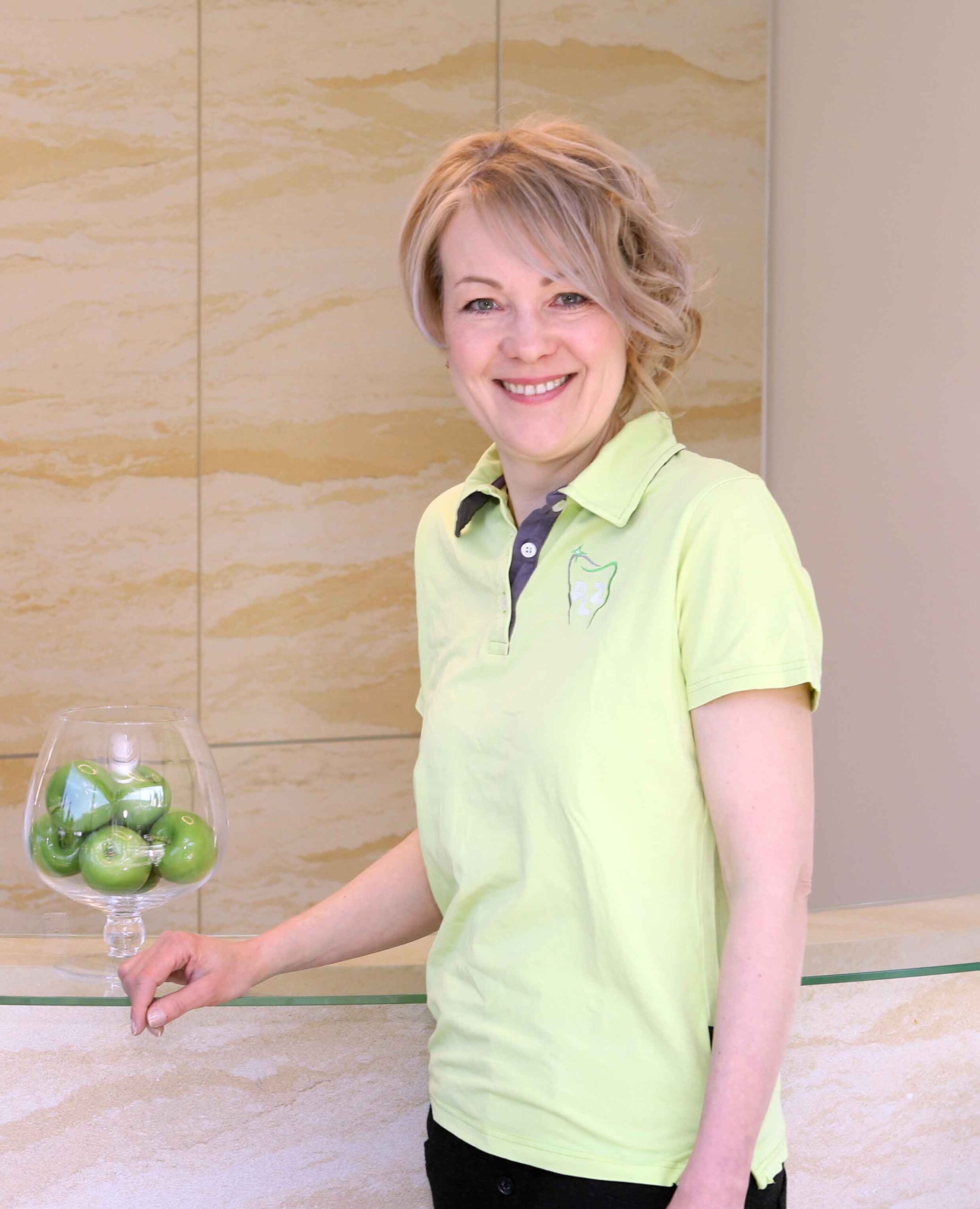Sabine Dutschke - Rezeption Frau steht an Rezeption einer Zahnarztpraxis